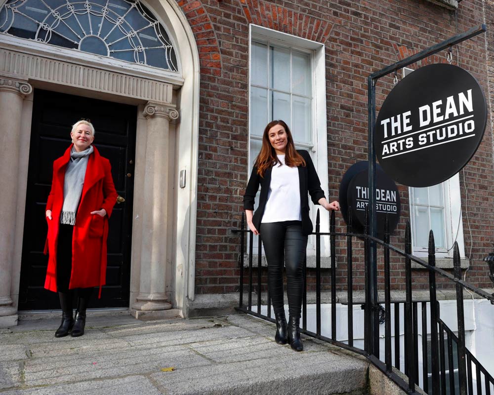 Photograph of Annie Fletcher, Director of IMMA and Laura Arnold, the Head of Marketing & PR for Press Up Entertainment Group outside a Georgian building with a sign saying 'The Dean Arts Studio'