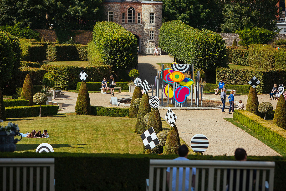Exterior installation photograph of a fountain in a formal garden, an installation of colourful shapes in the centre of the fountain.